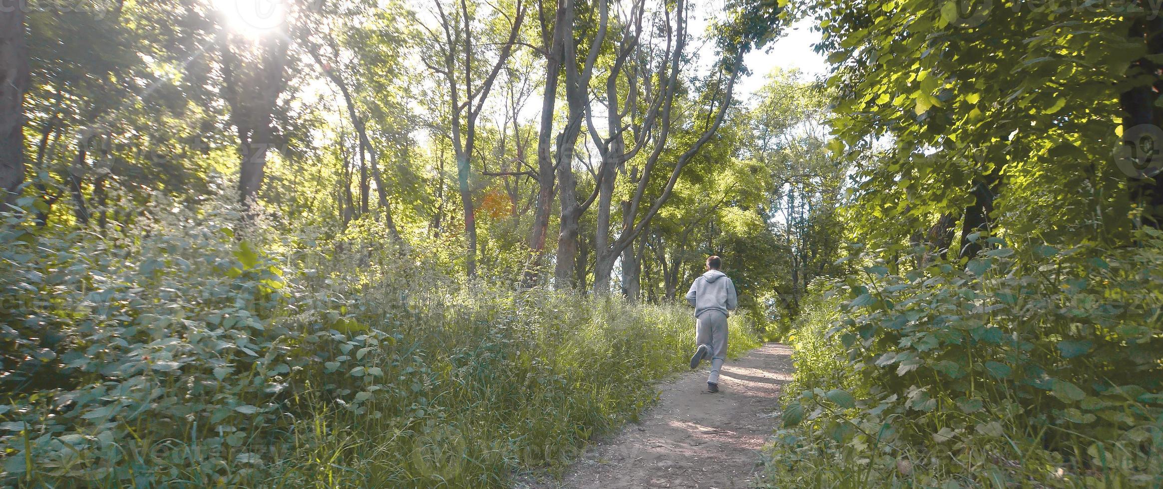 um jovem em um terno esportivo cinza corre ao longo do caminho entre os foto