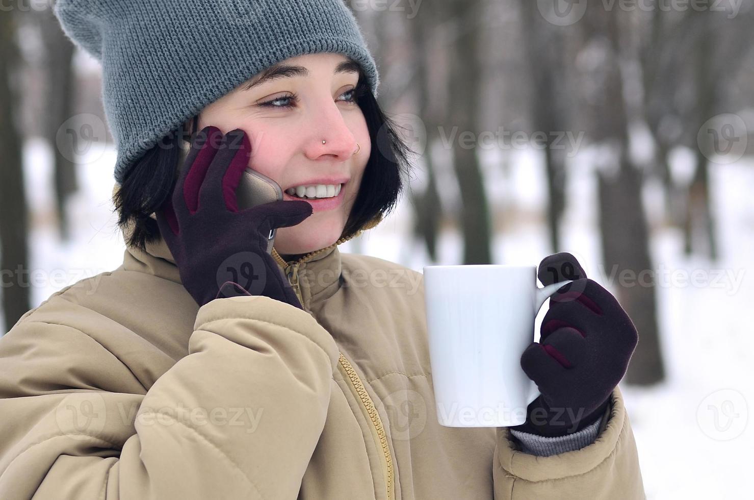 retrato de inverno de jovem com smartphone e xícara de café foto