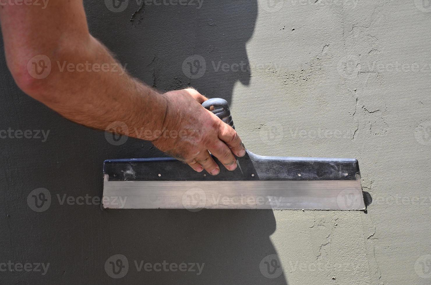 mãos de um velho trabalhador manual com ferramentas de reboco de parede renovando a casa. estucador renovando paredes externas e cantos com espátula e gesso. isolamento de parede. obras de acabamento foto