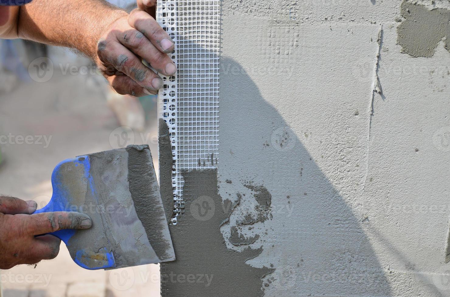 mãos de um velho trabalhador manual com ferramentas de reboco de parede renovando a casa. estucador renovando paredes externas e cantos com espátula e gesso. isolamento de parede. obras de acabamento foto