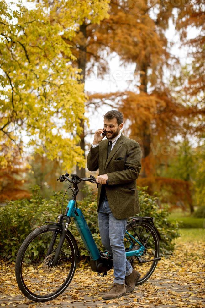jovem com bicicleta elétrica no parque outono foto