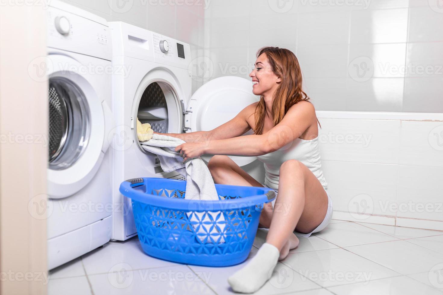 jovem tirando a roupa da máquina de lavar em casa. mulher carregando preparação máquina de lavar roupa no banheiro roupas na máquina de lavar foto