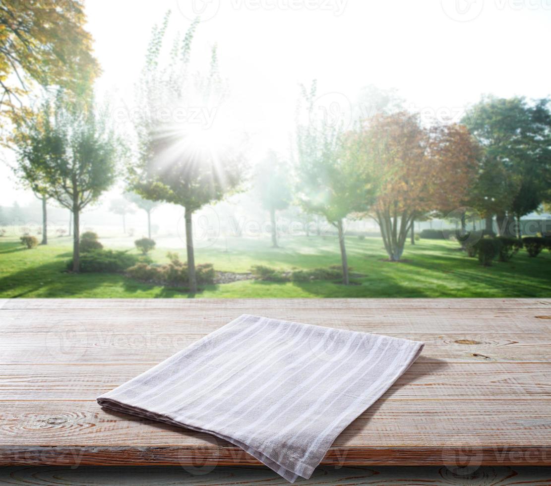 guardanapo branco, toalha de mesa na maquete de deck de madeira. fundo de paisagem de verão foto