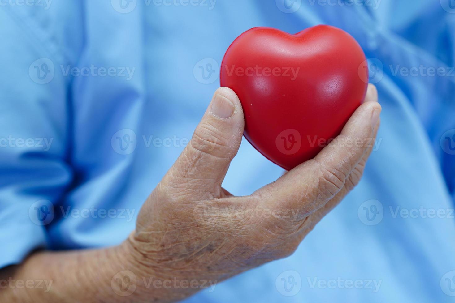 paciente asiática idosa idosa segurando coração vermelho no hospital. foto