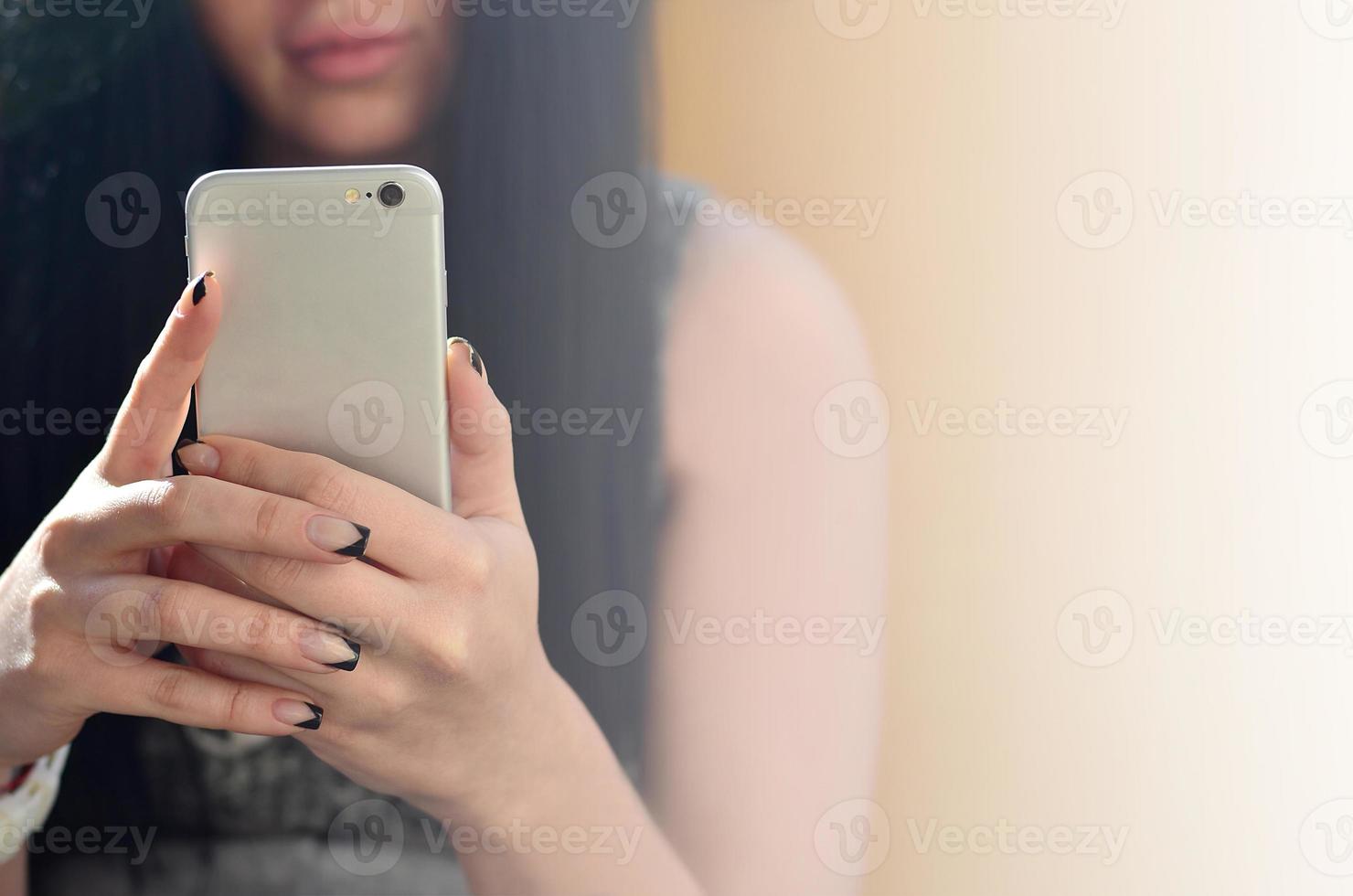 a menina morena usa um smartphone de toque moderno foto