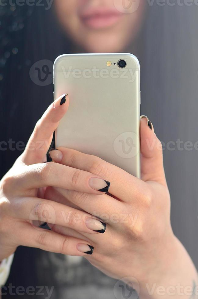 a menina morena tira selfie em um smartphone de toque moderno foto