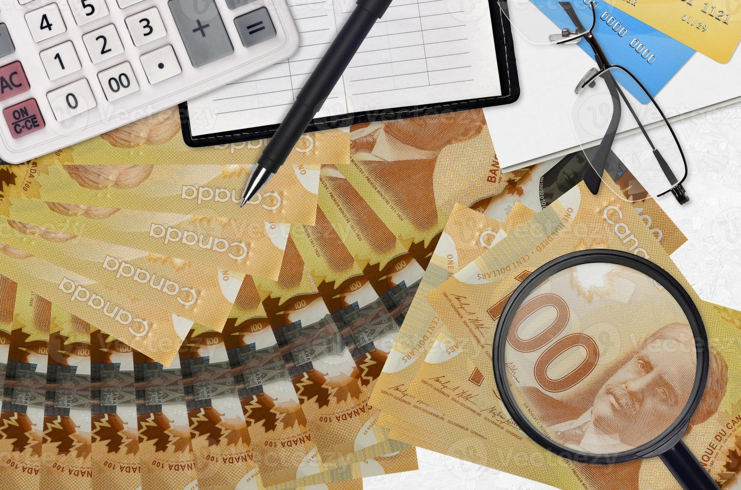 Notas de 100 dólares canadenses e calculadora com óculos e caneta. conceito de temporada de pagamento de impostos ou soluções de investimento. procurando um emprego com salário alto foto