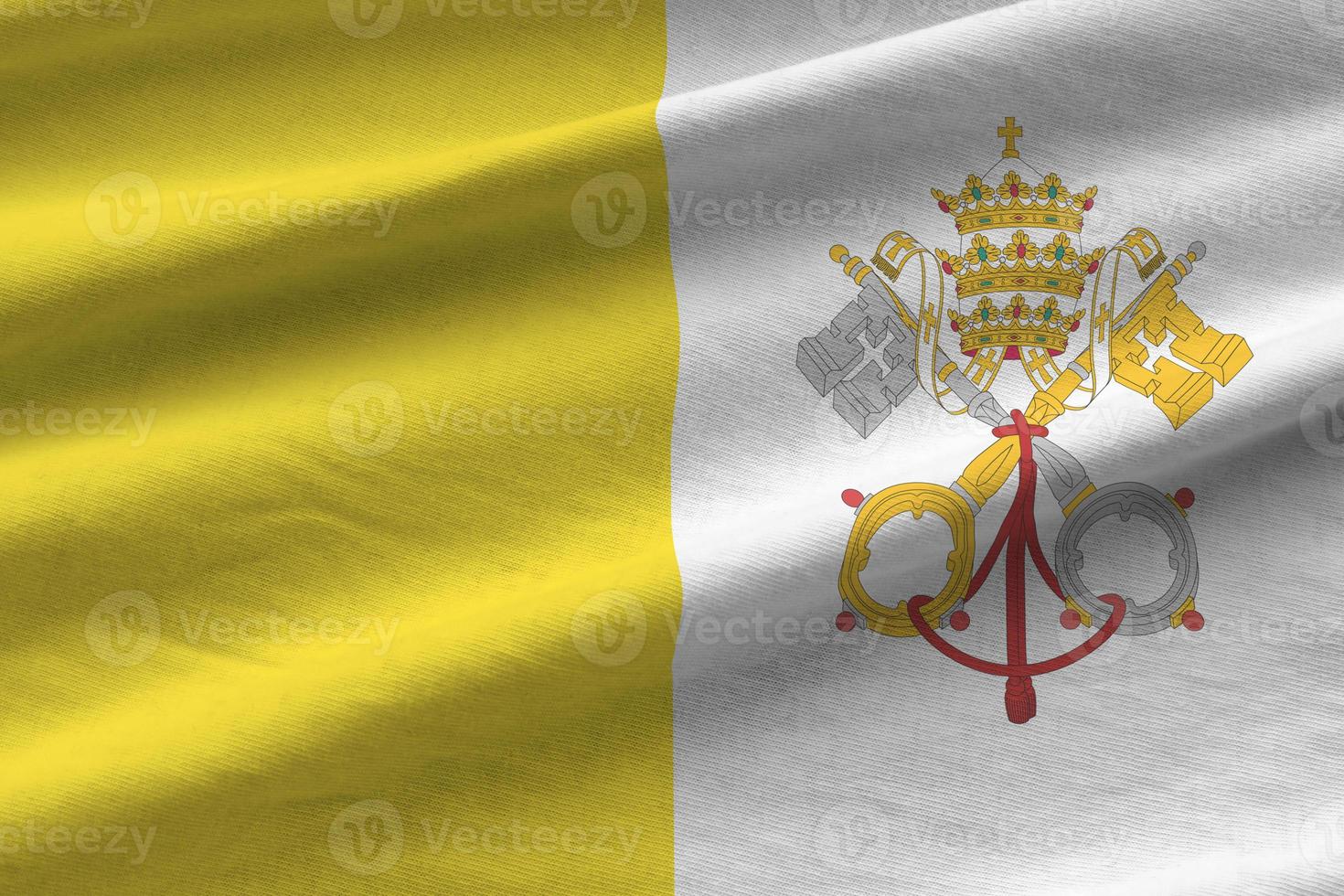 bandeira do estado da cidade do vaticano com grandes dobras acenando perto sob a luz do estúdio dentro de casa. os símbolos e cores oficiais no banner foto