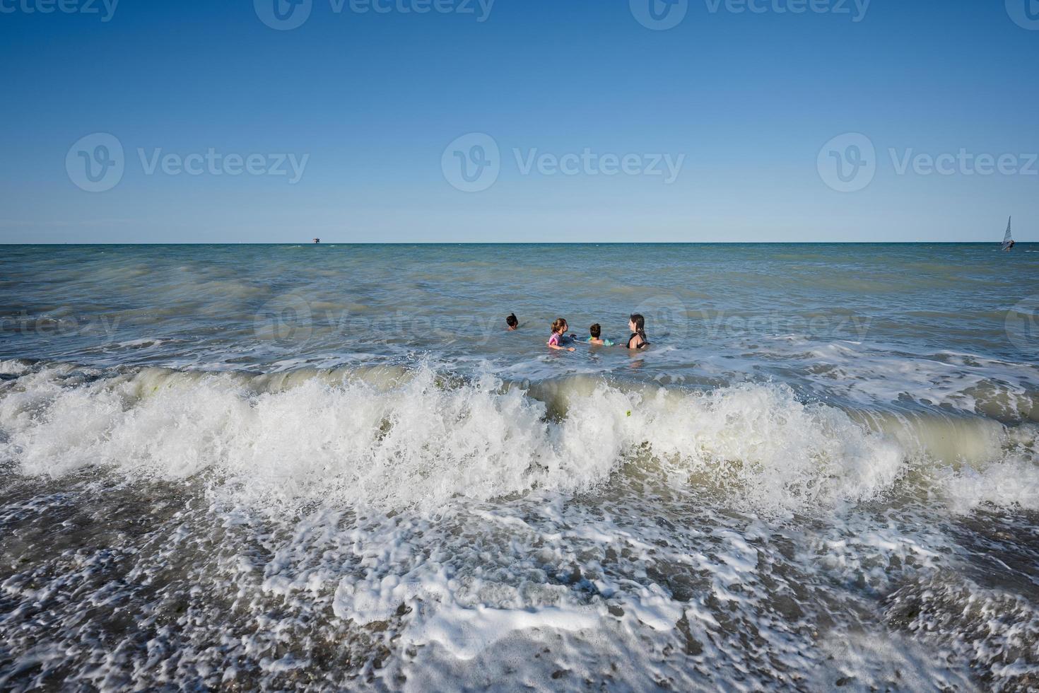 família com crianças nadando no mar adriático na praia porto sant elpidio, itália. foto