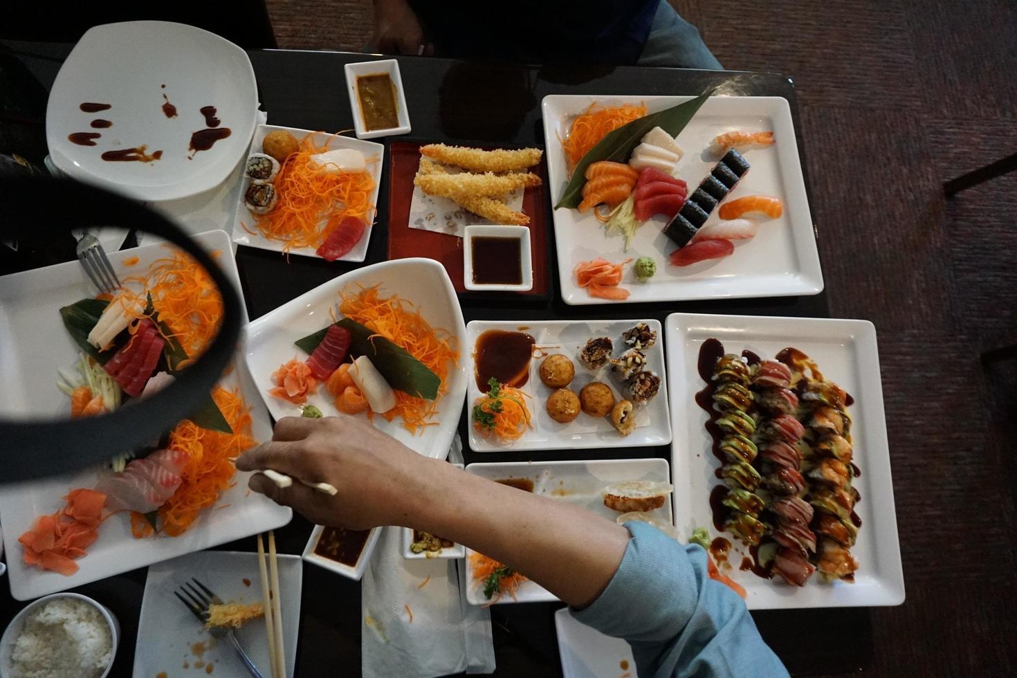 vários menus, sushi, sashimi, nigiri, carne de porco frita e sopa de missô. sashimi, sashimi chutoro, pauzinhos de comida japonesa e wasabi na mesa preta, estilo de comida japonesa. desfoca o foco. foto