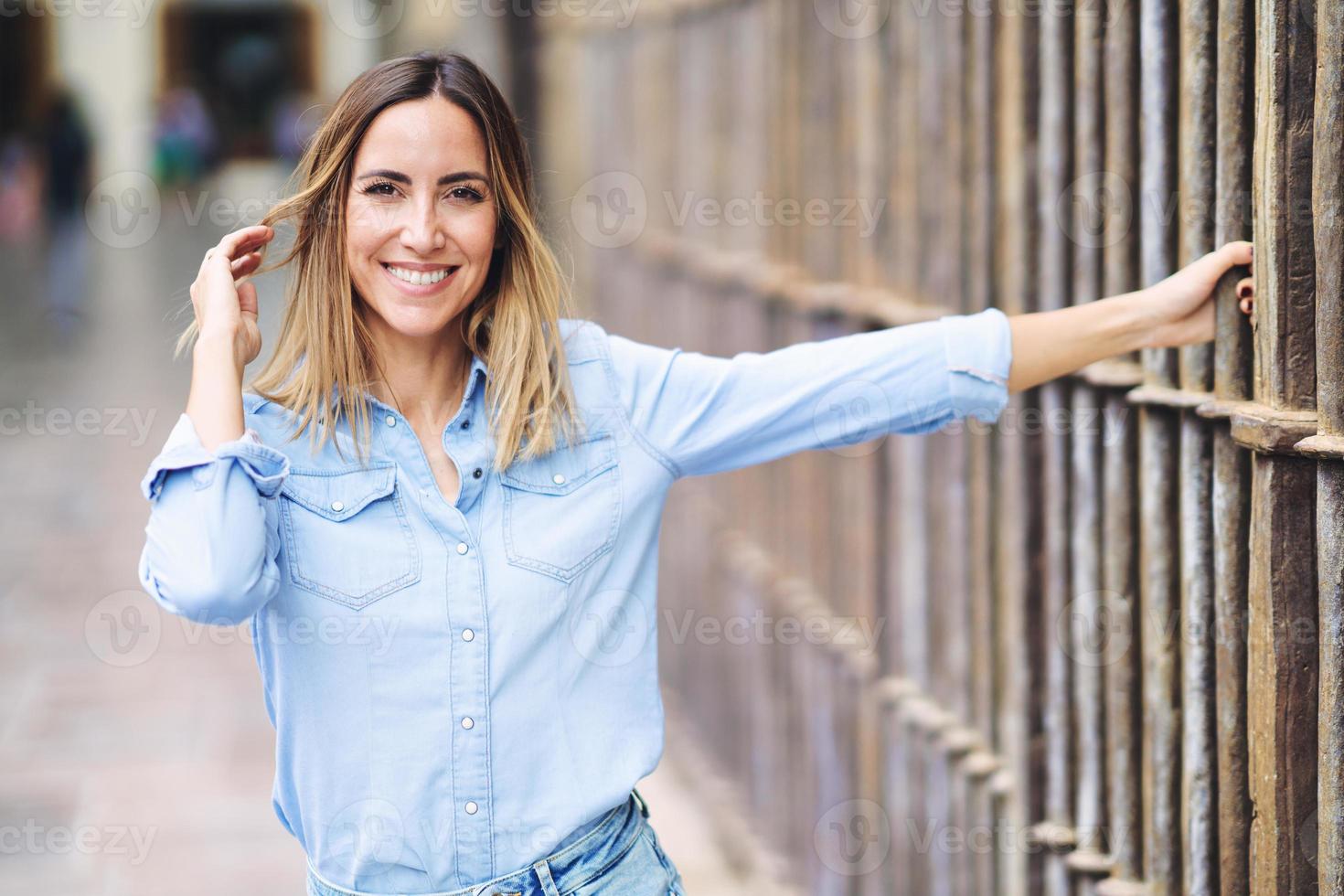 mulher alegre tocando o cabelo perto da cerca foto