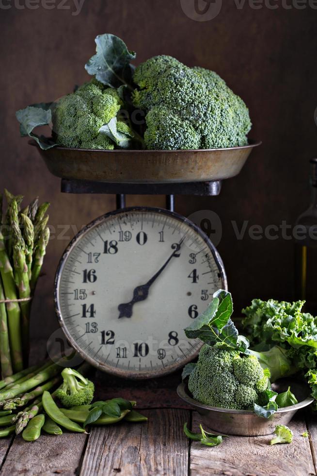 vegetais verdes frescos em balanças de cozinha velhas foto