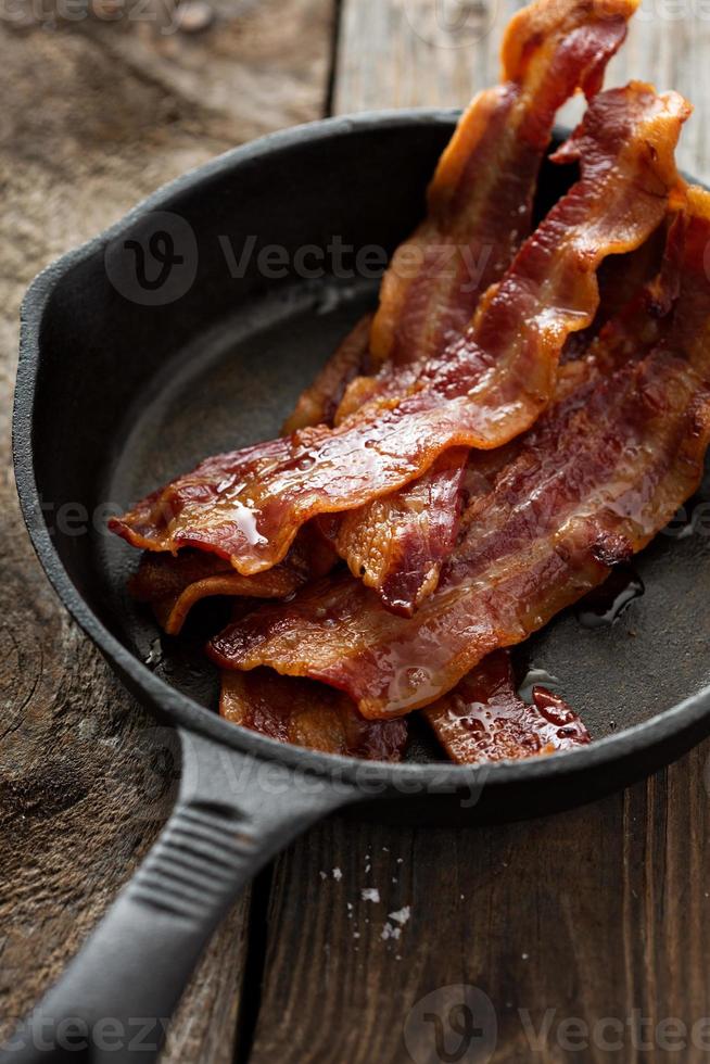 bacon quente escaldante em uma frigideira de ferro fundido foto