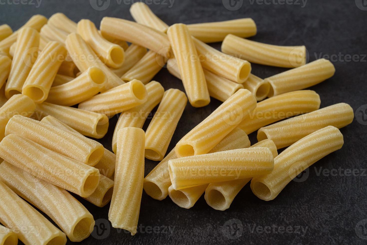 macarrão penne rigate italiano cru isolado em fundo preto foto