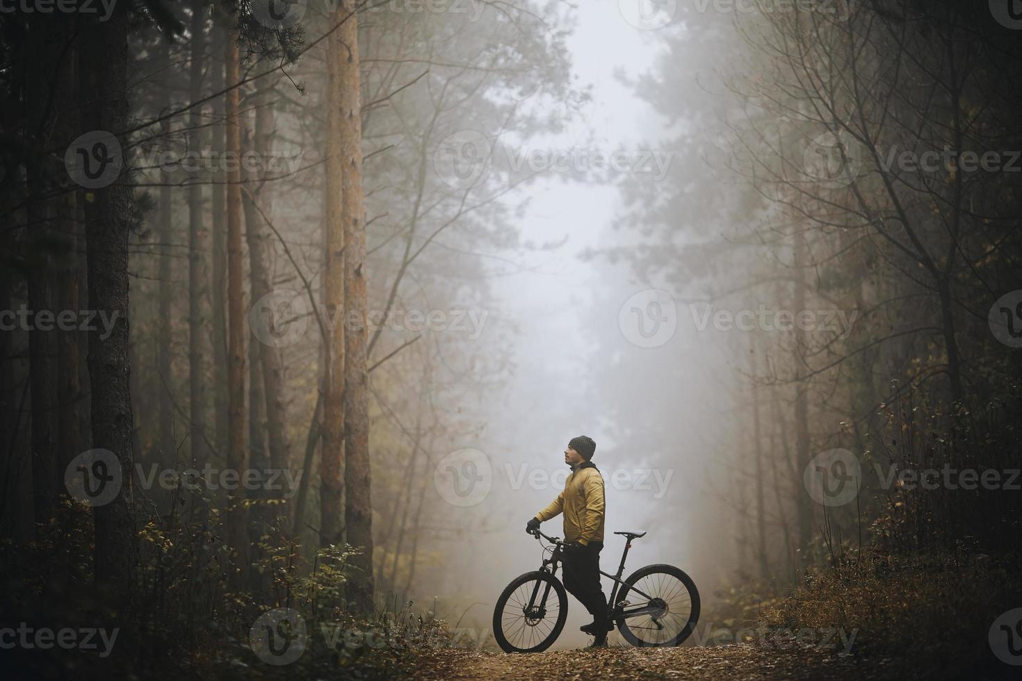 jovem pegando um freio durante o ciclismo pela floresta de outono foto