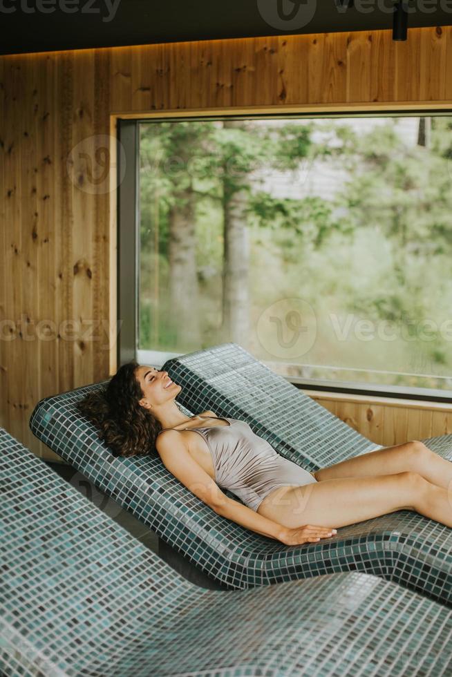 jovem relaxante na cama tepidarium no spa foto