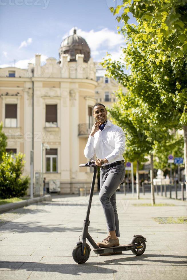 jovem afro-americano usando scooter elétrico em uma rua foto