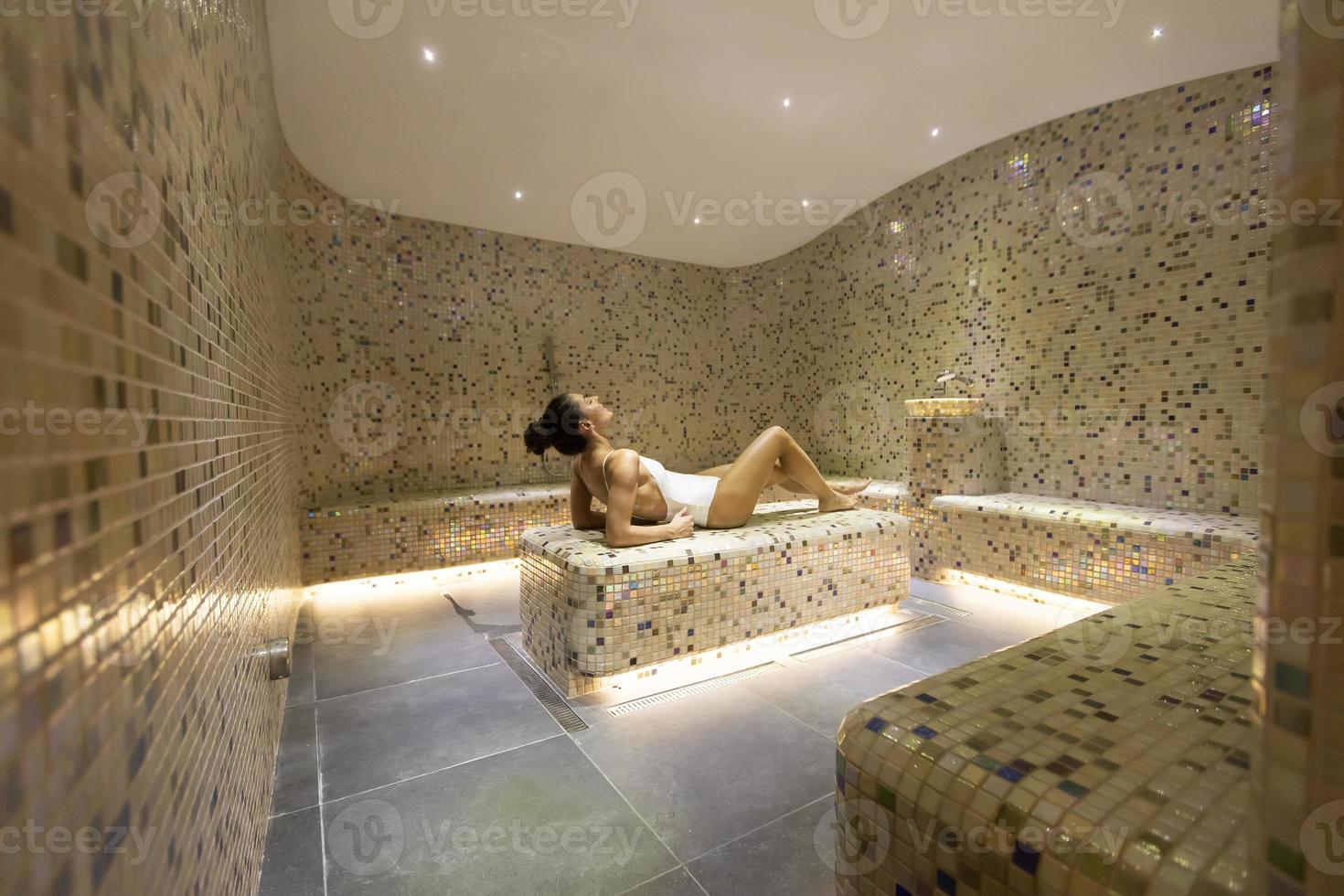 jovem relaxante na cama tepidarium no spa foto