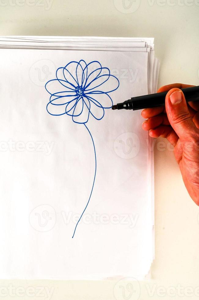 mão desenhando uma flor no papel foto