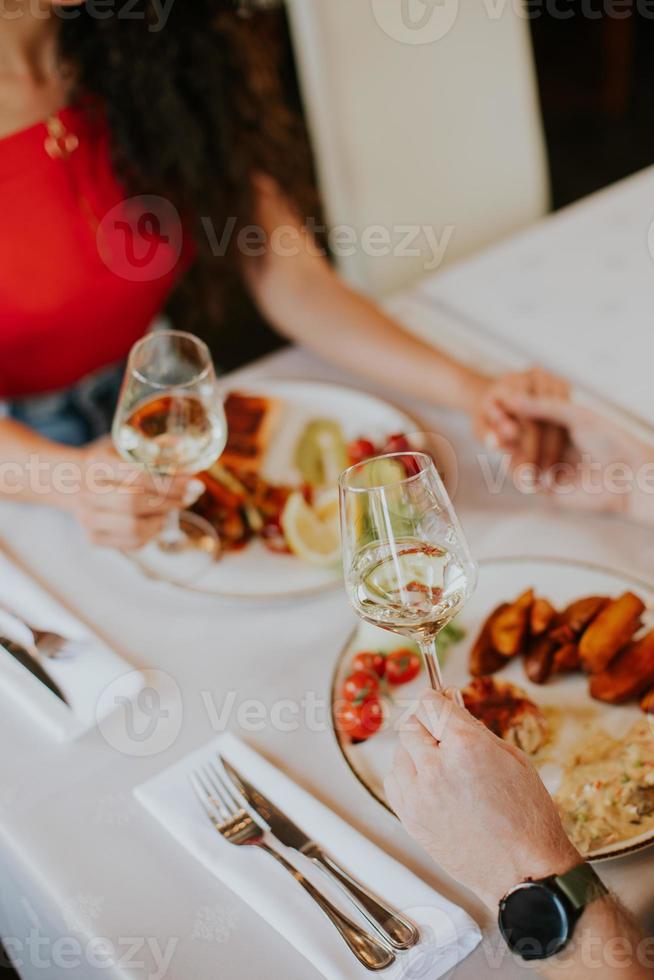 jovem casal almoçando com vinho branco no restaurante foto