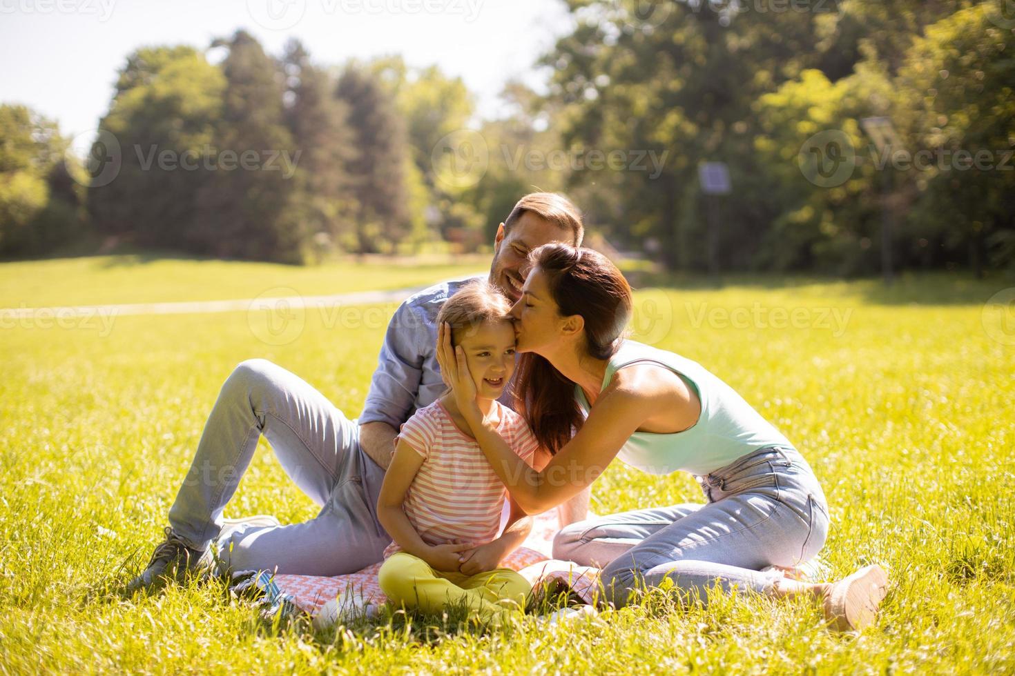 família jovem e feliz com a filhinha se divertindo no parque em um dia ensolarado foto