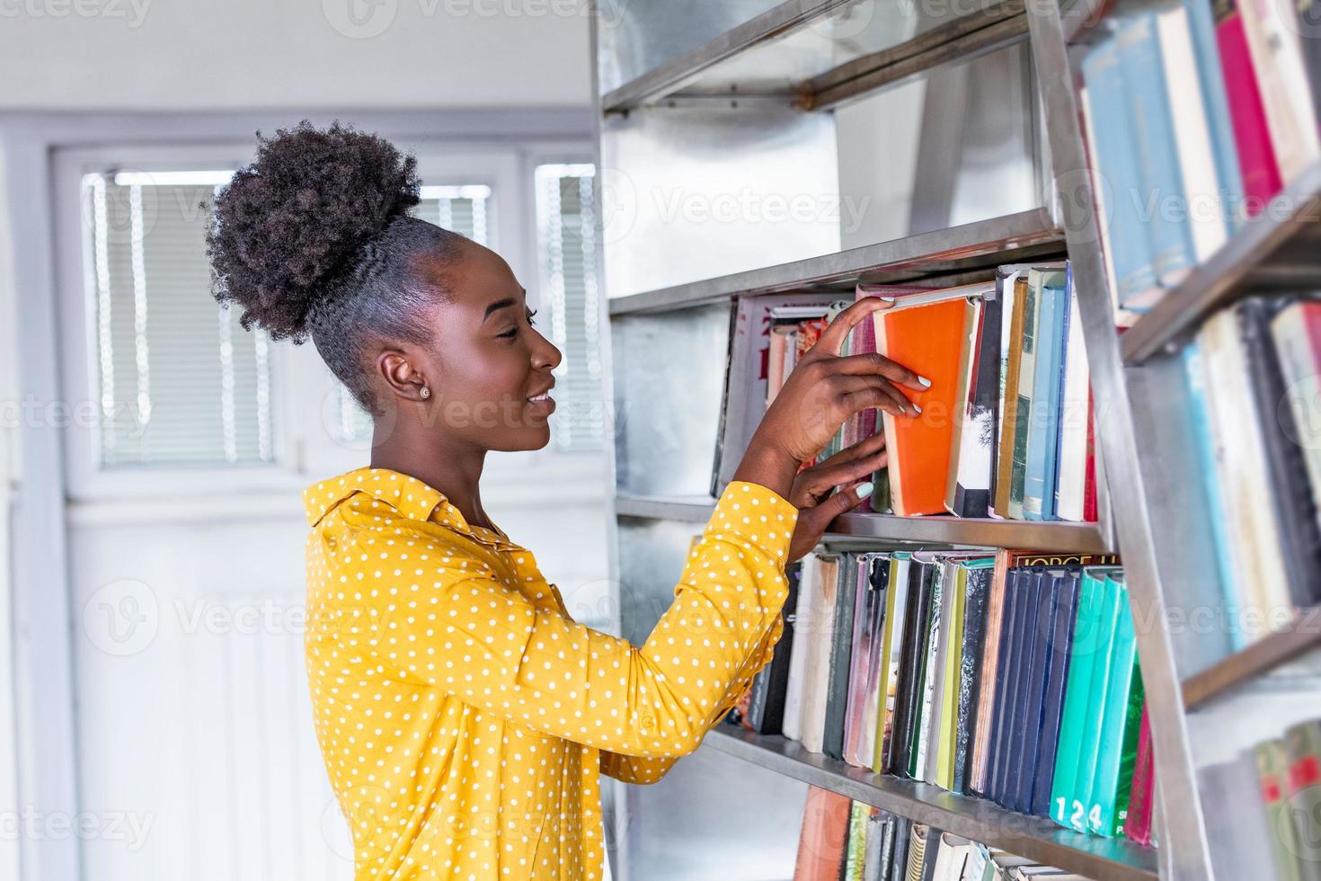 mulher tirando livro da estante da biblioteca. jovem bibliotecário procurando livros e tirando um livro da estante da biblioteca foto