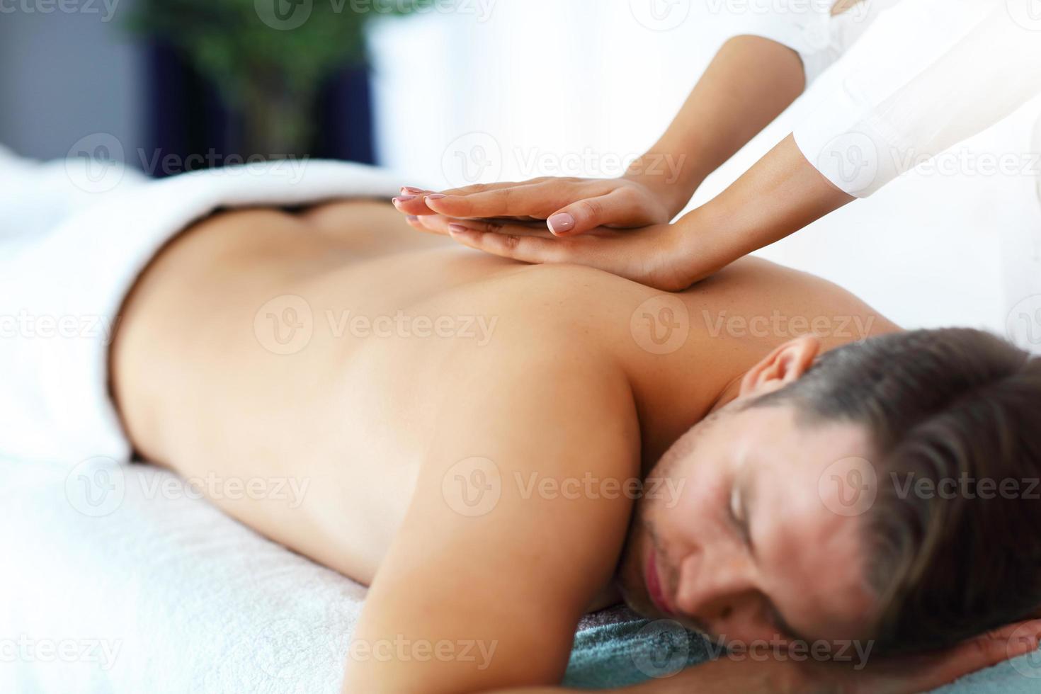 homem bonito tendo massagem no salão spa foto