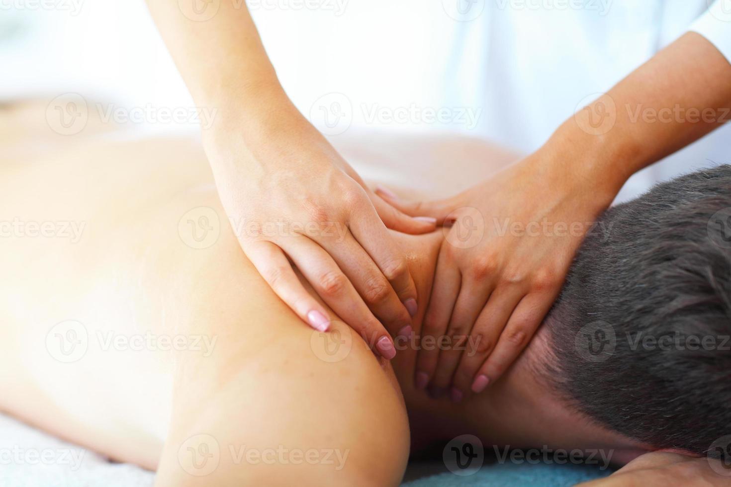 homem bonito tendo massagem no salão spa foto