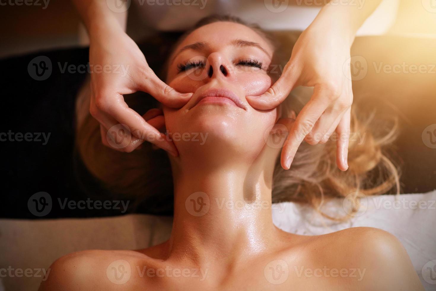 mulher feliz tendo massagem facial no salão spa foto