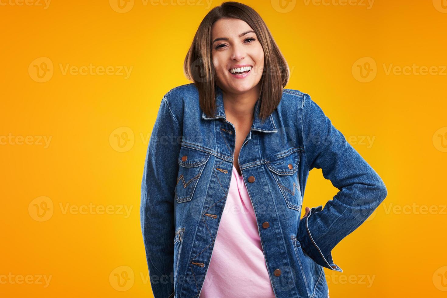 close-up da mulher em jaqueta jeans, olhando para a câmera sobre fundo amarelo foto