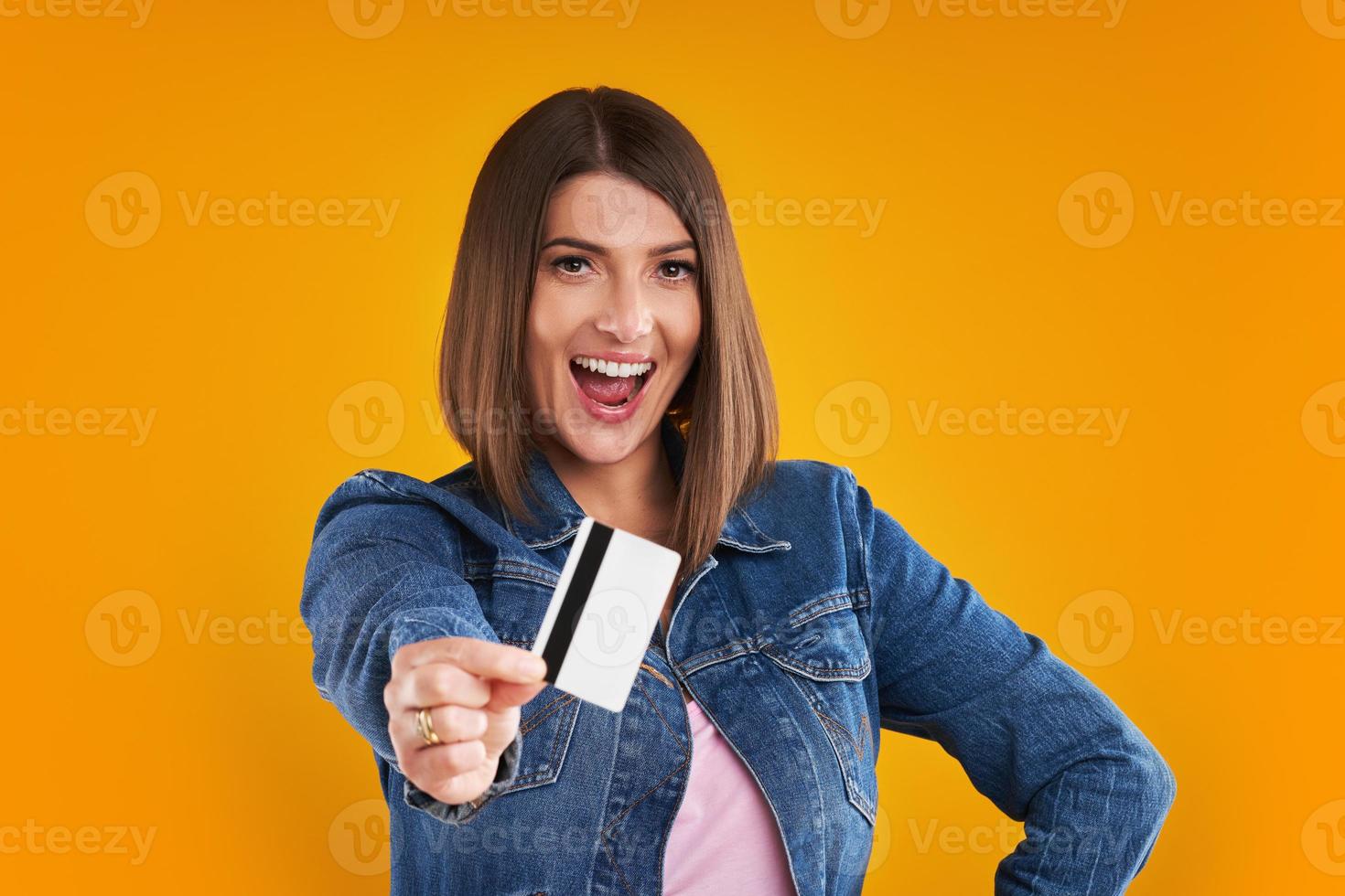 close-up da mulher em jaqueta jeans com sacolas de compras sobre fundo amarelo foto