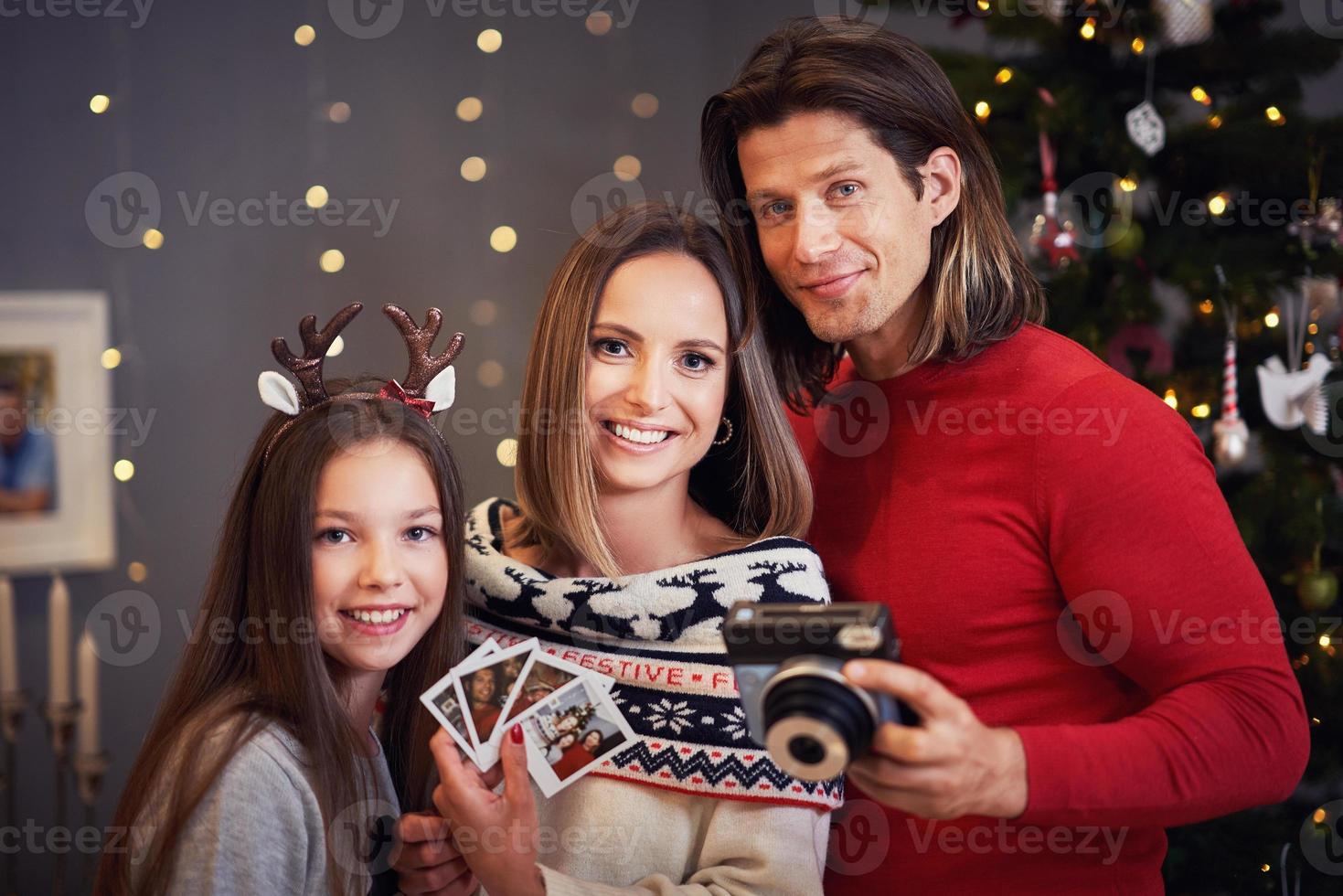 linda família comemorando o natal em casa e tirando fotos instantâneas