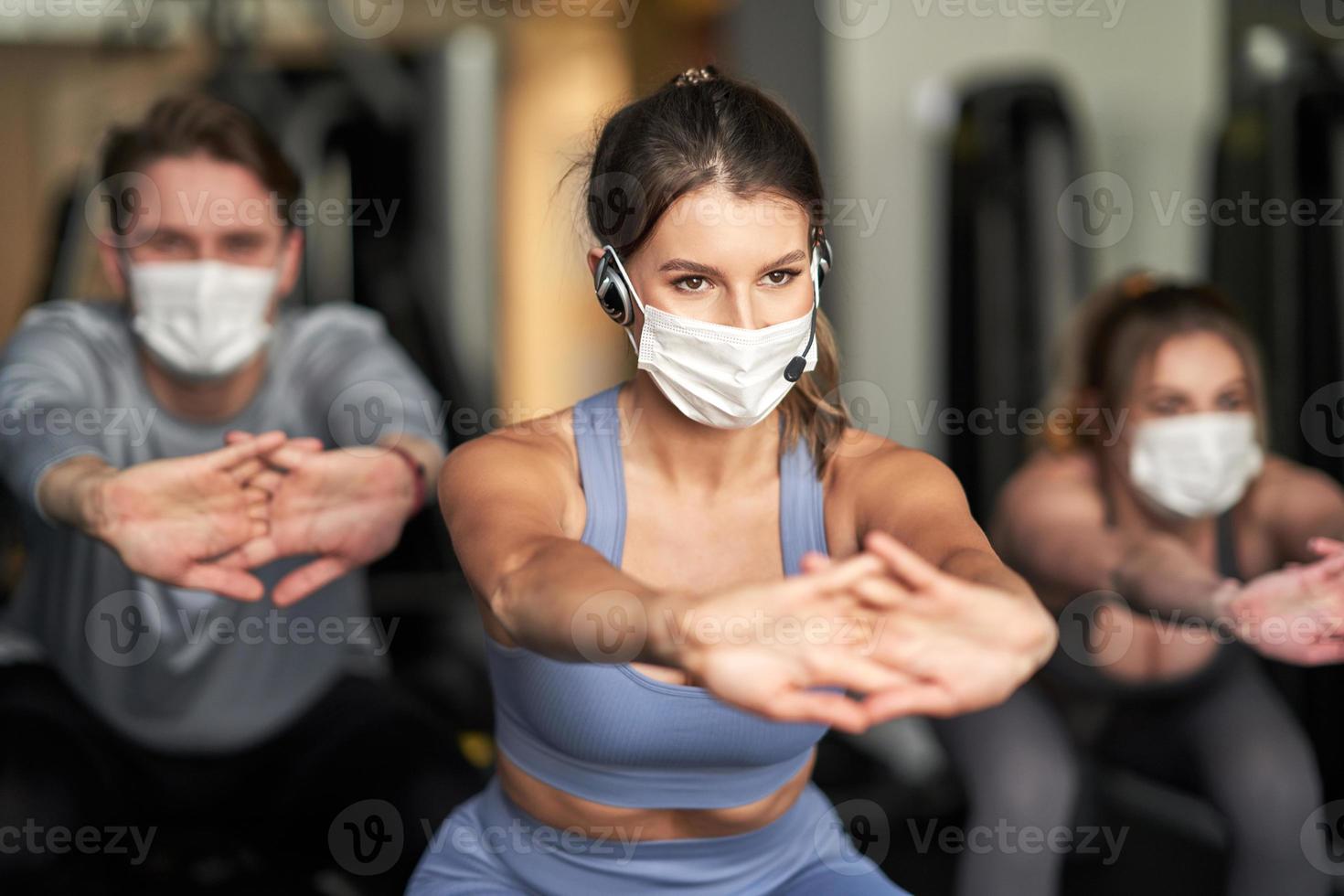 grupo de pessoas usando máscaras malhando em uma academia foto