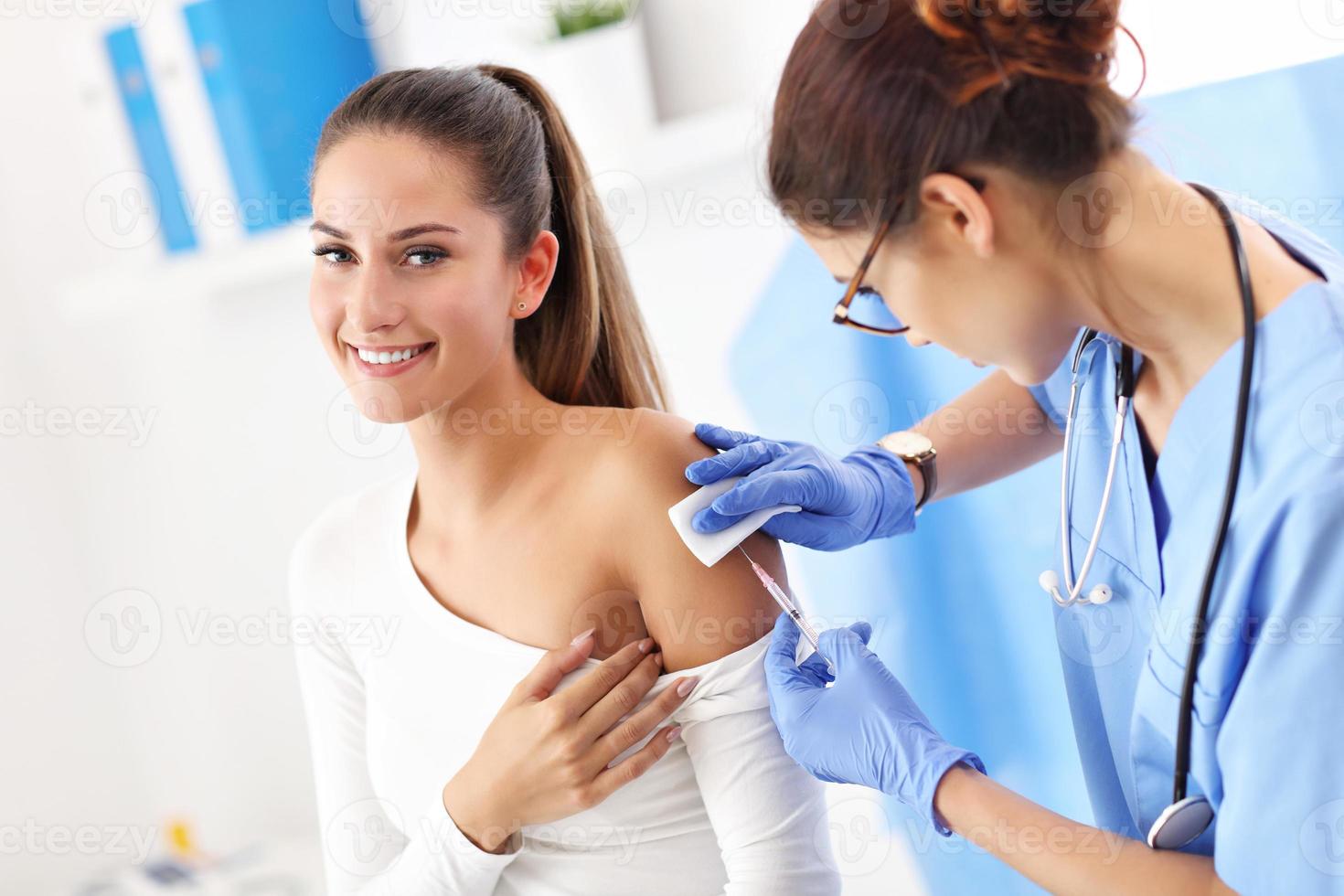 mulher adulta tomando injeção durante visita ao consultório médico feminino foto