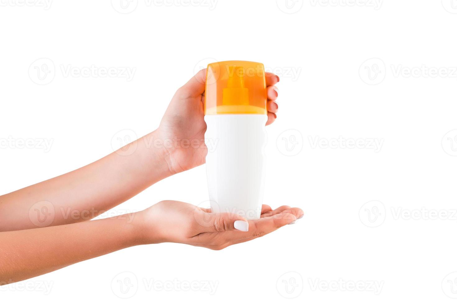 mão feminina segurando o frasco de creme de loção isolado. garota dá produtos cosméticos em fundo branco foto