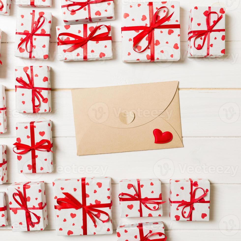 fundo romântico do dia dos namorados. cartão envelope com caixas de presente e coração em um fundo de madeira foto