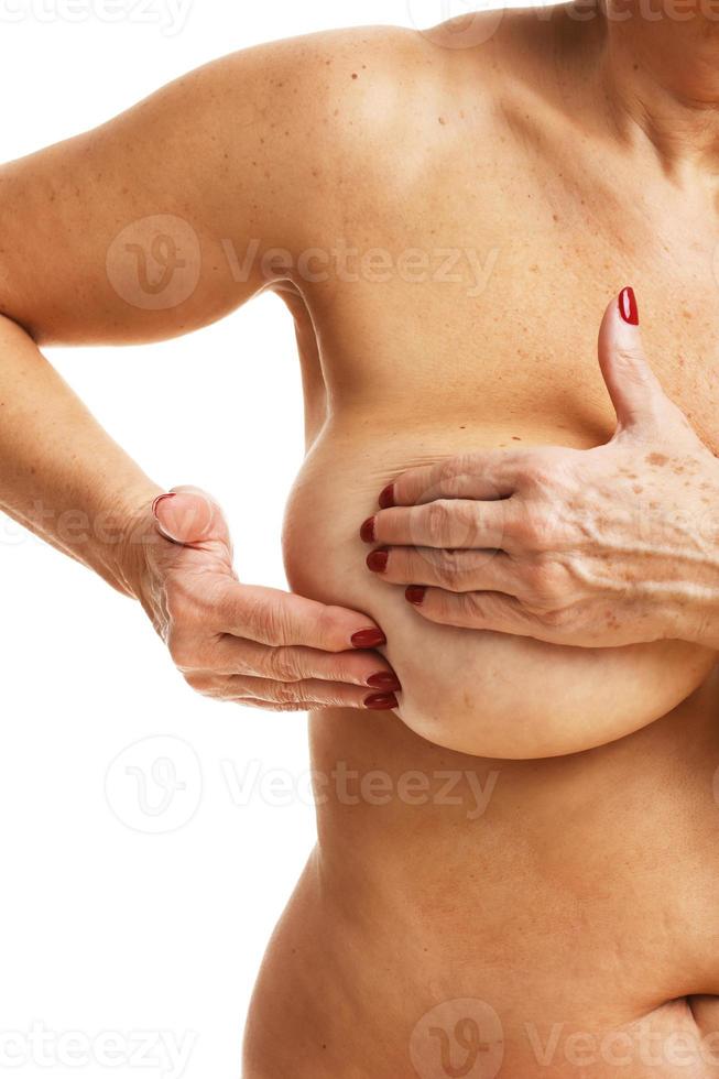 mulher adulta examinando a mama sobre fundo branco foto