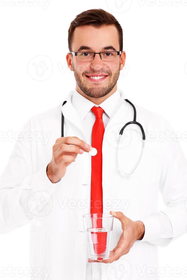 médico segurando pílula e copo de água foto