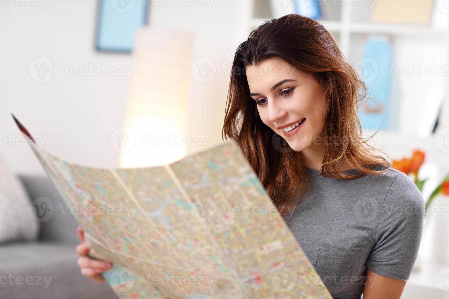 mulher feliz com mapa em casa planejando férias foto
