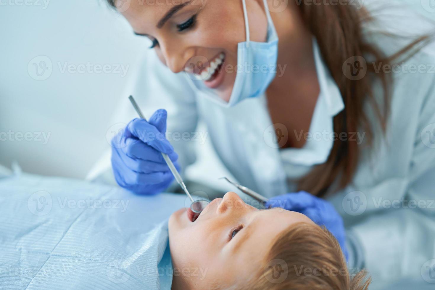 menino e dentista feminina no consultório de dentistas foto