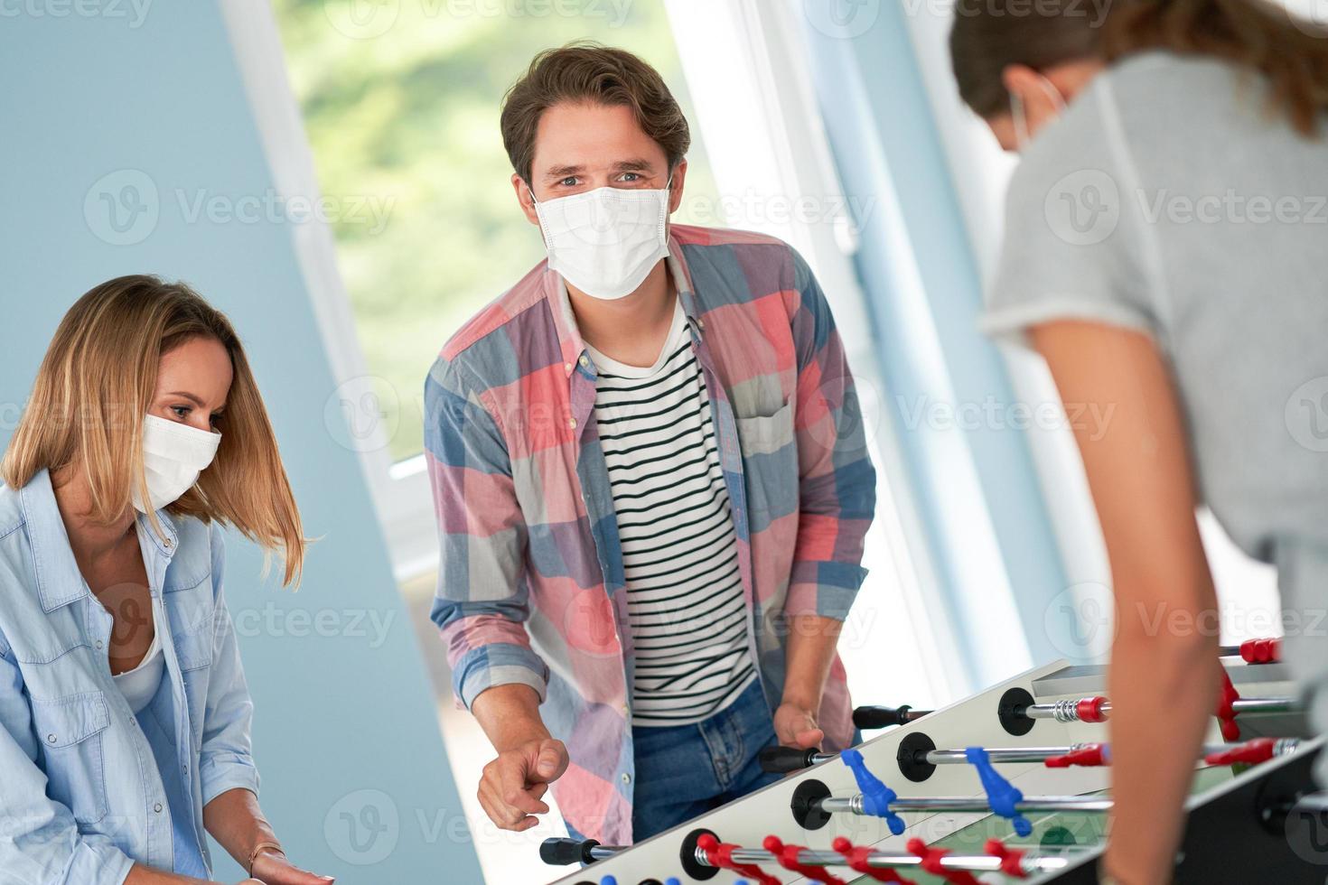 casal de estudantes usando máscaras jogando futebol de mesa no campus foto