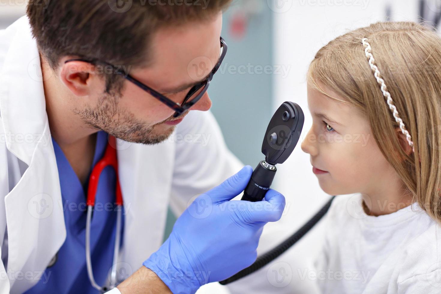 criança optometrista masculino examina a visão da menina foto