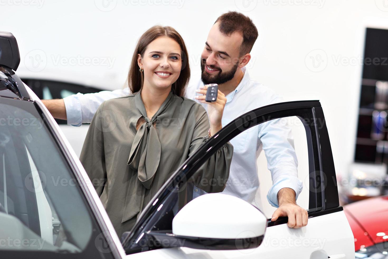 casal adulto escolhendo carro novo no showroom foto