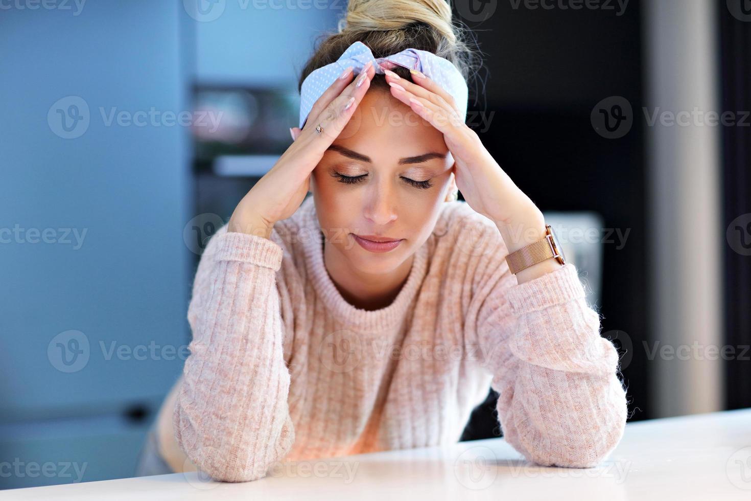 mulher milenar cansada descansando a cabeça na cozinha foto