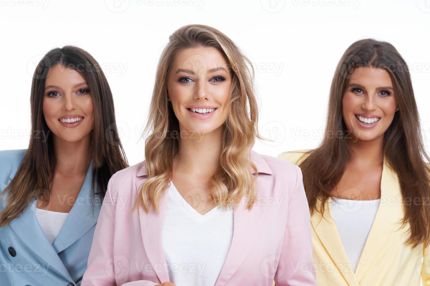 três mulheres em ternos pastel posando sobre fundo branco foto
