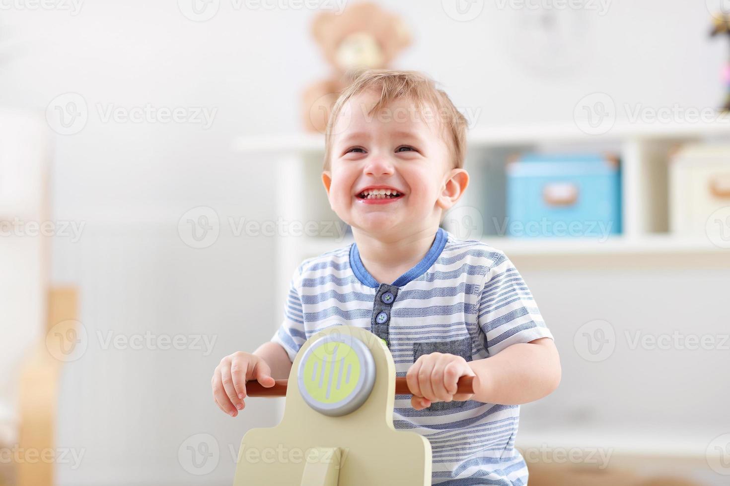 menino alegre balançando em uma cadeira de balanço em forma de scooter foto