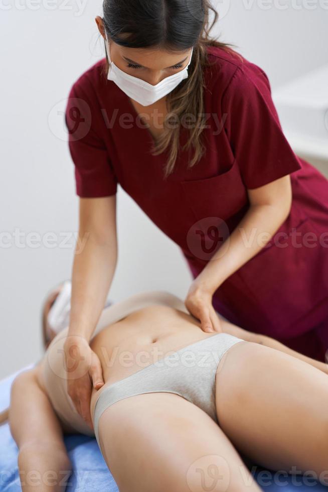 fisioterapeuta em máscara ajudando paciente do sexo feminino foto