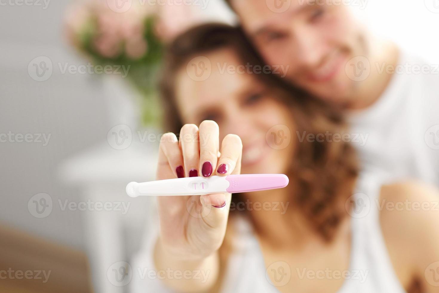 casal feliz com teste de gravidez no quarto foto