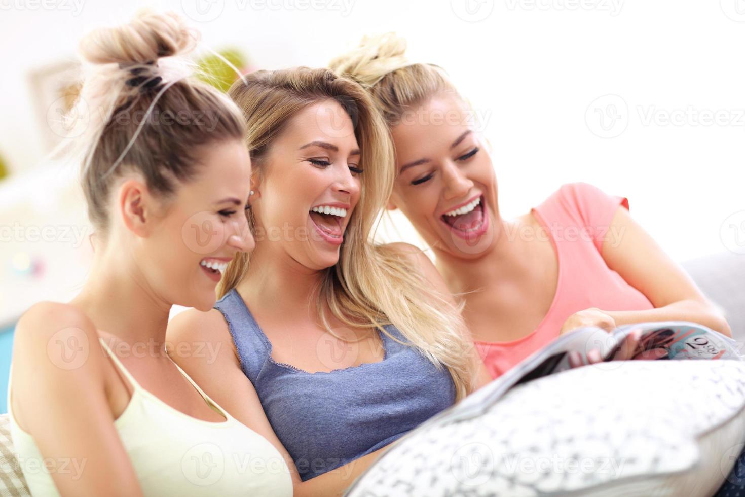 três mulheres bonitas relaxando em casa e lendo revista foto