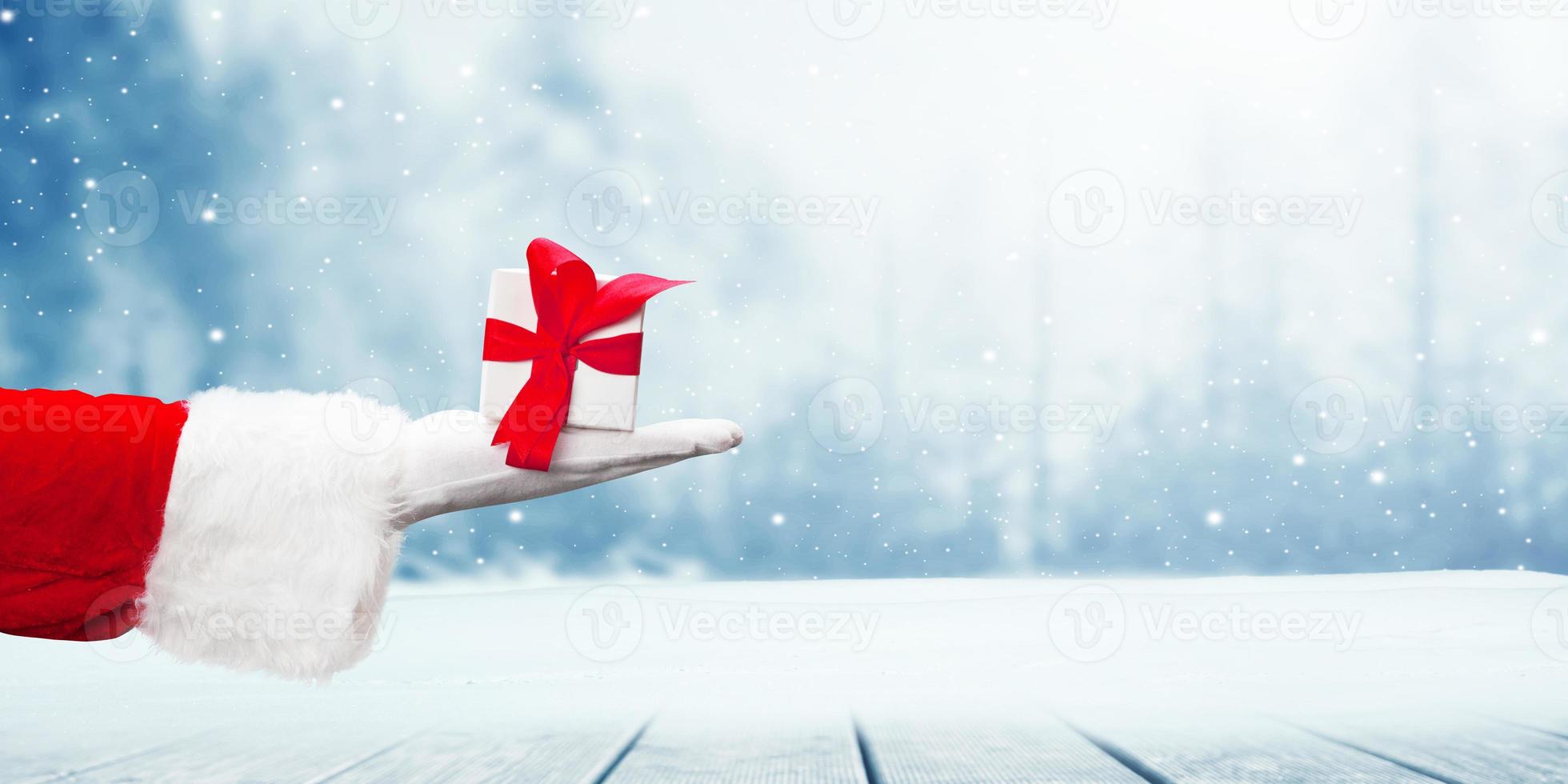 mão de Papai Noel segurando um presente de Natal embrulhado. foto